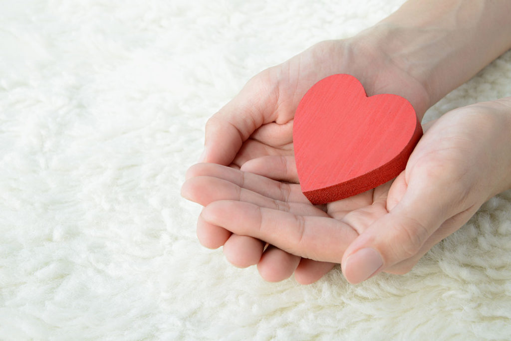 Hands holding a wooden heart